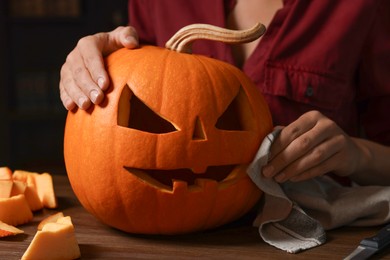 Photo of Woman with carved pumpkin for Halloween at wooden table, closeup