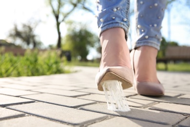 Woman stepping in chewing gum on sidewalk. Concept of stickiness