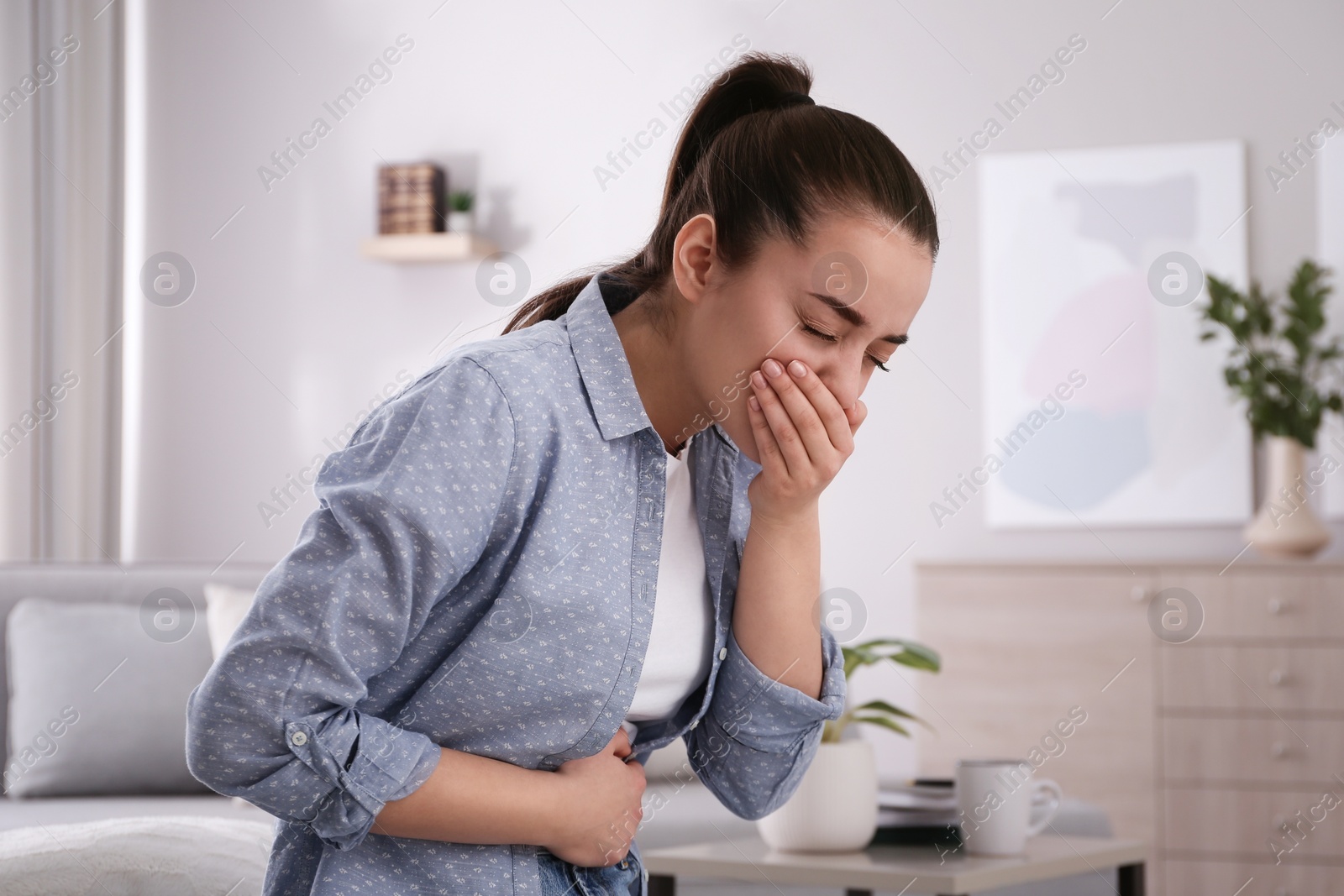 Photo of Young woman suffering from nausea at home. Food poisoning