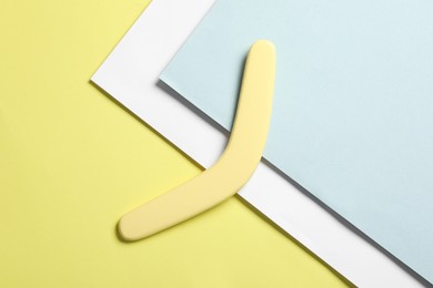 Photo of Yellow wooden boomerang on color background, top view