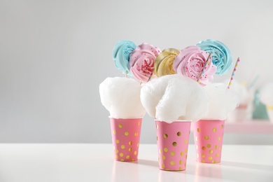 Photo of Cups with cotton candy dessert on table, space for text