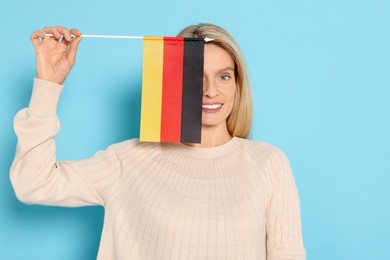 Photo of Woman with flag of Germany on light blue background