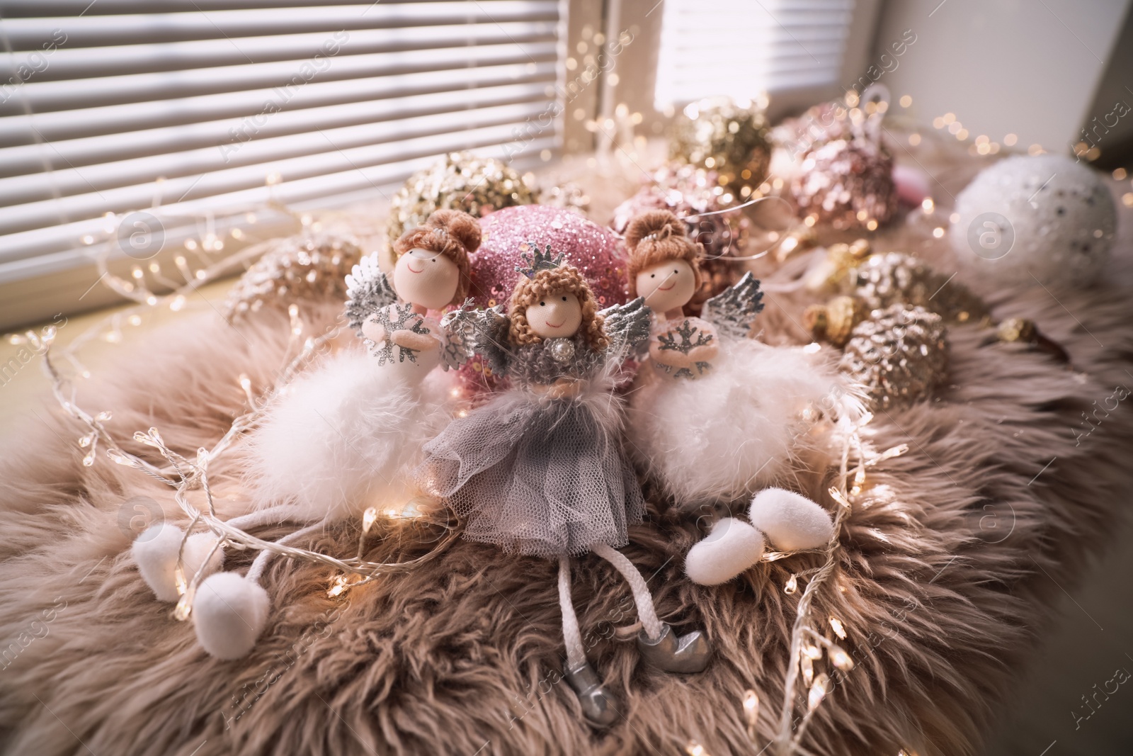 Photo of Beautiful angel dolls and shiny bauble on window sill indoors