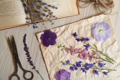 Photo of Flat lay composition with beautiful dried flowers, book and scissors on wooden table