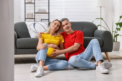 Young family housing concept. Pregnant woman with her husband on floor at home