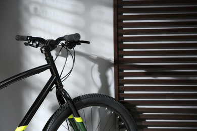 Photo of Modern black bicycle near grey wall indoors, closeup