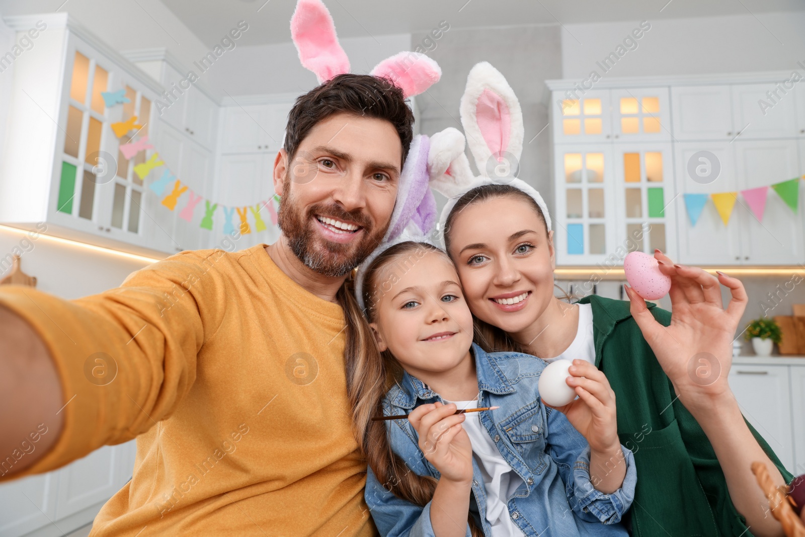 Photo of Happy family making selfie while painting Easter eggs in kitchen