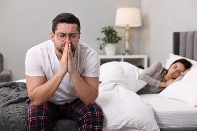 Stressed husband after quarrel with his wife in bedroom, selective focus. Relationship problems