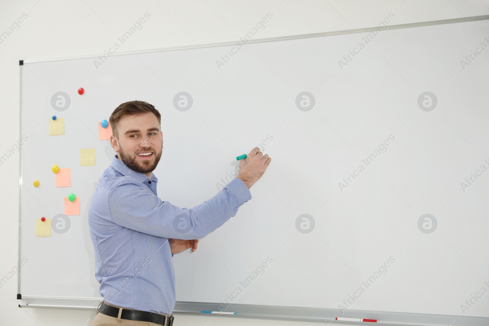 Photo of Young teacher writing on whiteboard in classroom. Space for text