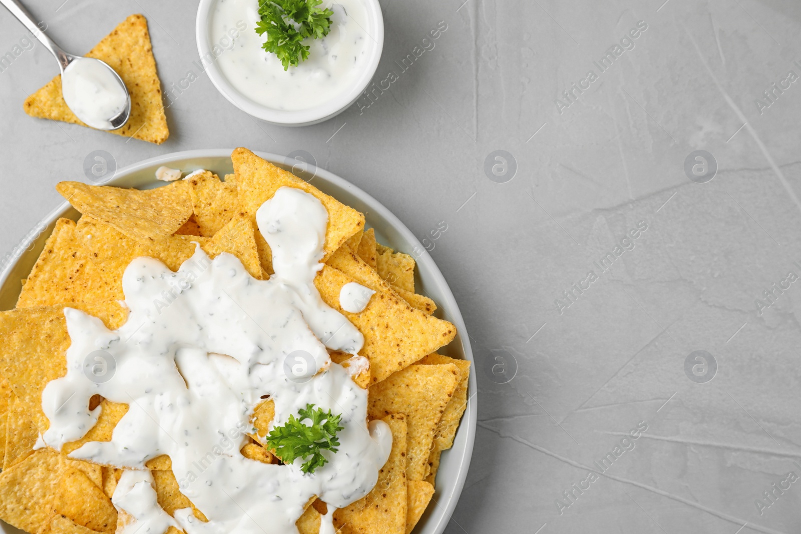 Photo of Plate of Mexican nacho chips with sauce on grey stone background, flat lay. Space for text