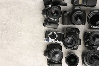Photo of Modern cameras on gray textured table, flat lay. Space for text
