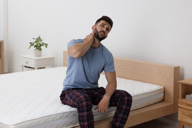 Photo of Man suffering from neck pain after sleeping on uncomfortable mattress at home