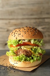 Photo of Burger with delicious patty on gray table