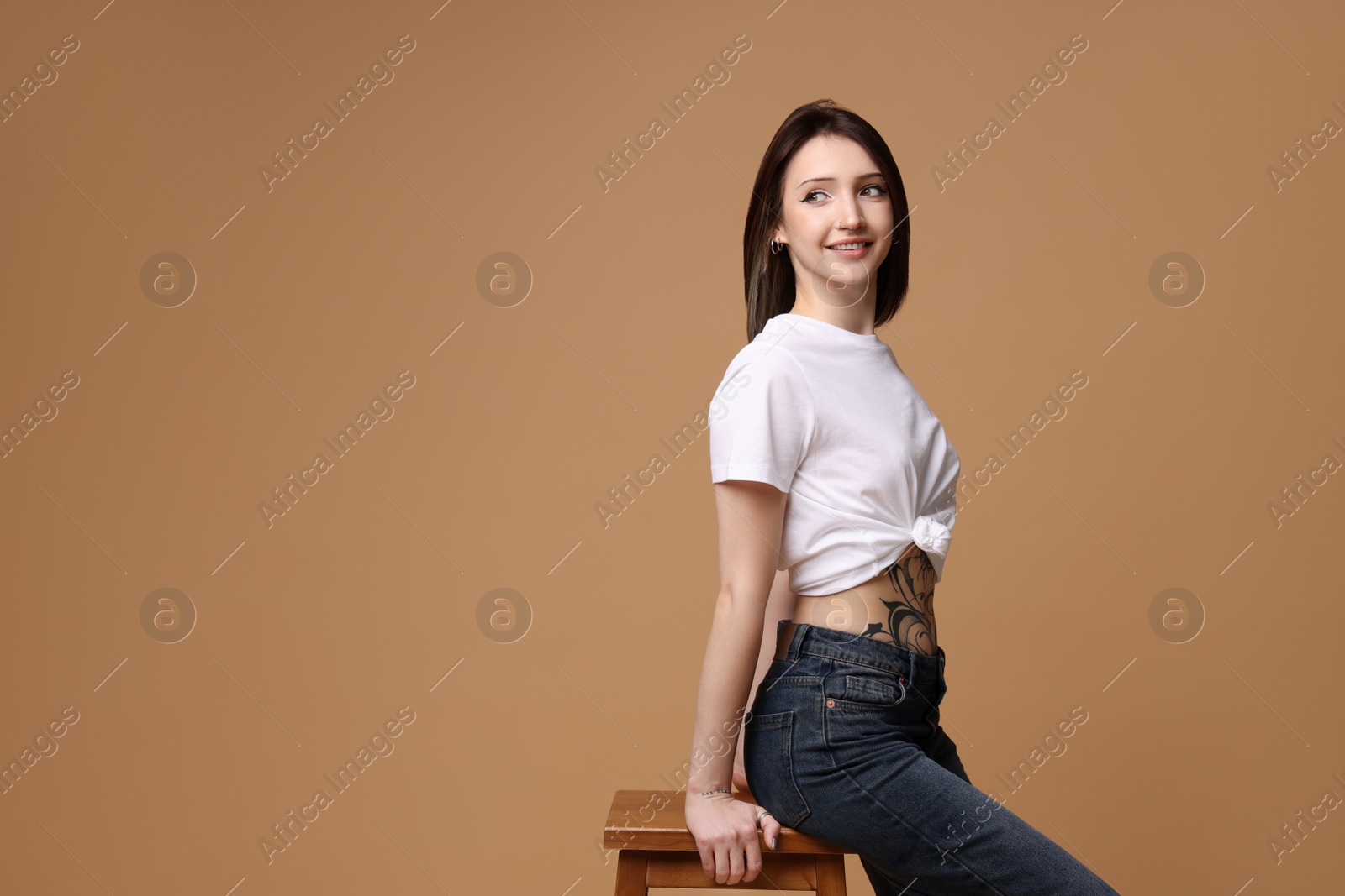 Photo of Portrait of smiling tattooed woman on beige background. Space for text