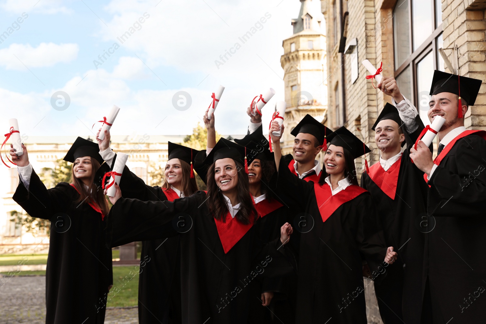 Photo of Happy students with diplomas outdoors. Graduation ceremony