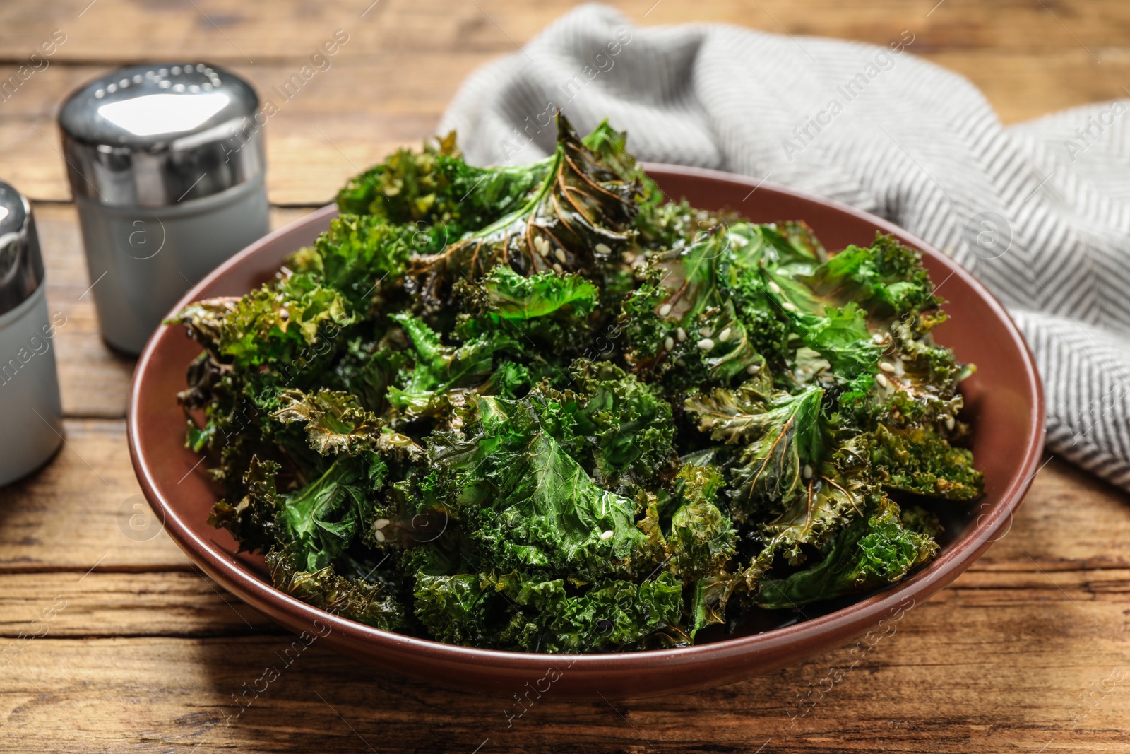 Photo of Tasty baked fresh kale chips on wooden table