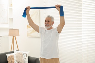 Photo of Senior man doing exercise with fitness elastic band at home