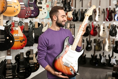 Young man with guitar in music store