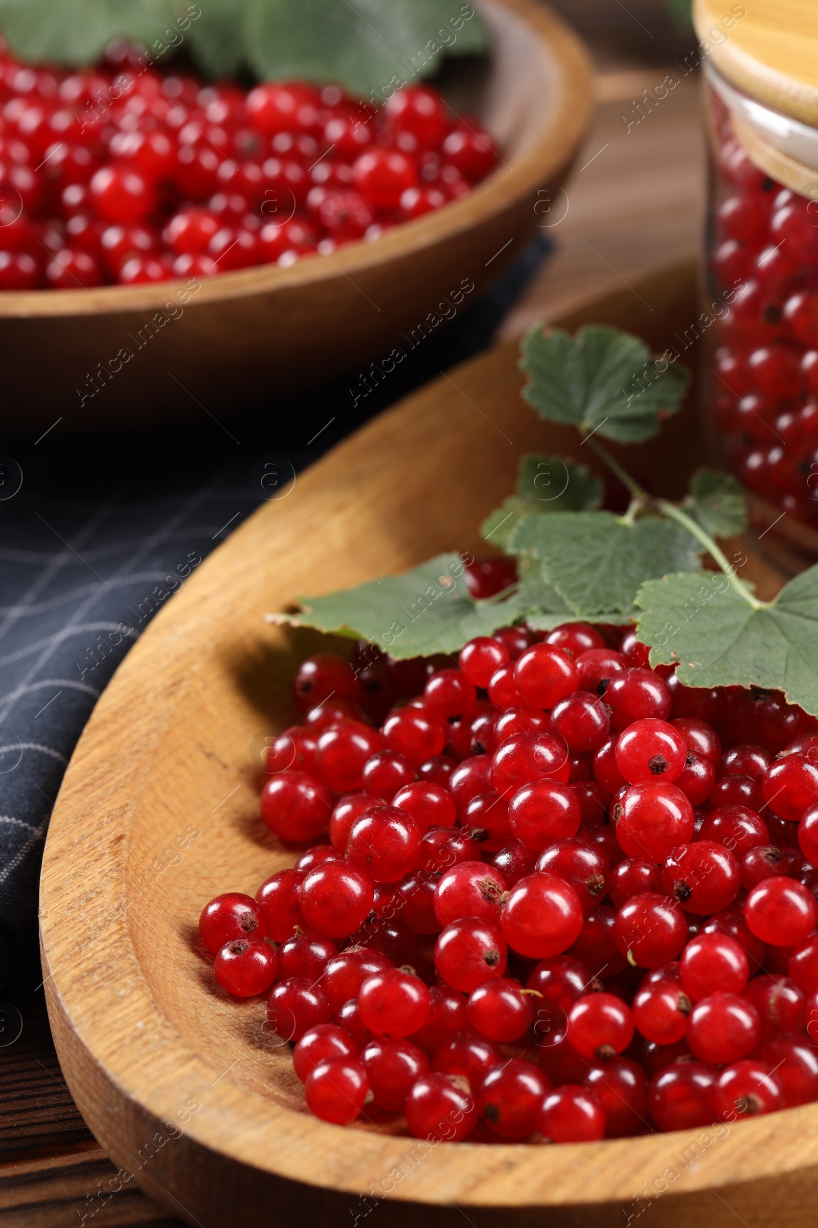 Photo of Ripe red currants and leaves on wooden table, closeup