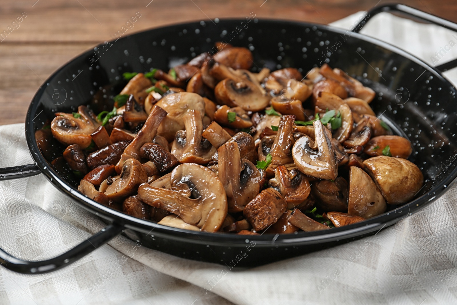 Photo of Frying pan with mushrooms on wooden table