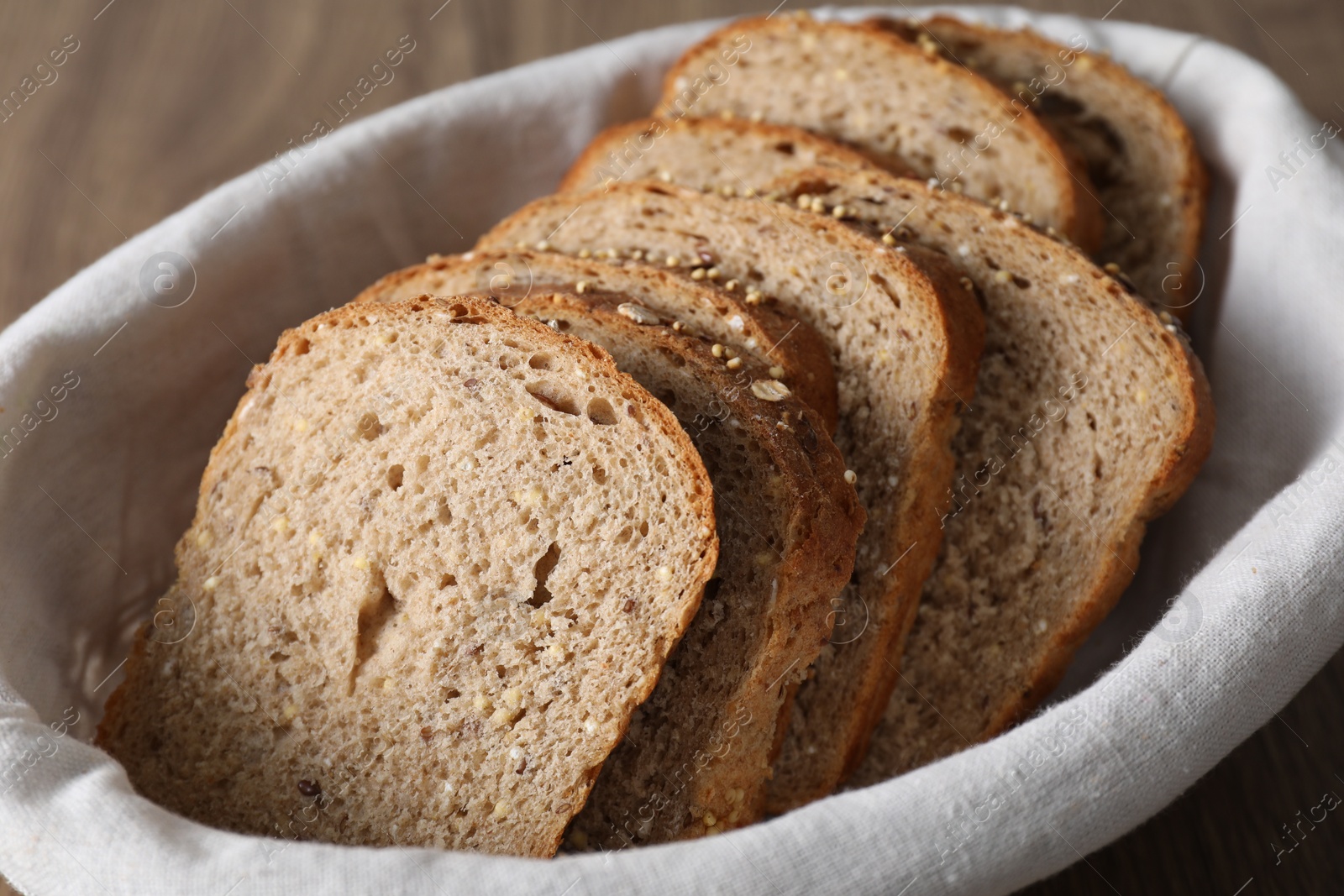 Photo of Slices of fresh bread on cloth in basket, closeup