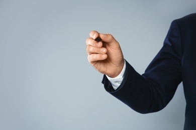 Businessman writing against grey background, closeup view of hand with space for text