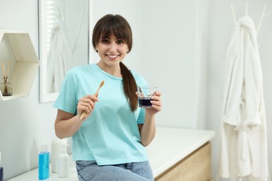 Photo of Young woman with mouthwash and toothbrush in bathroom