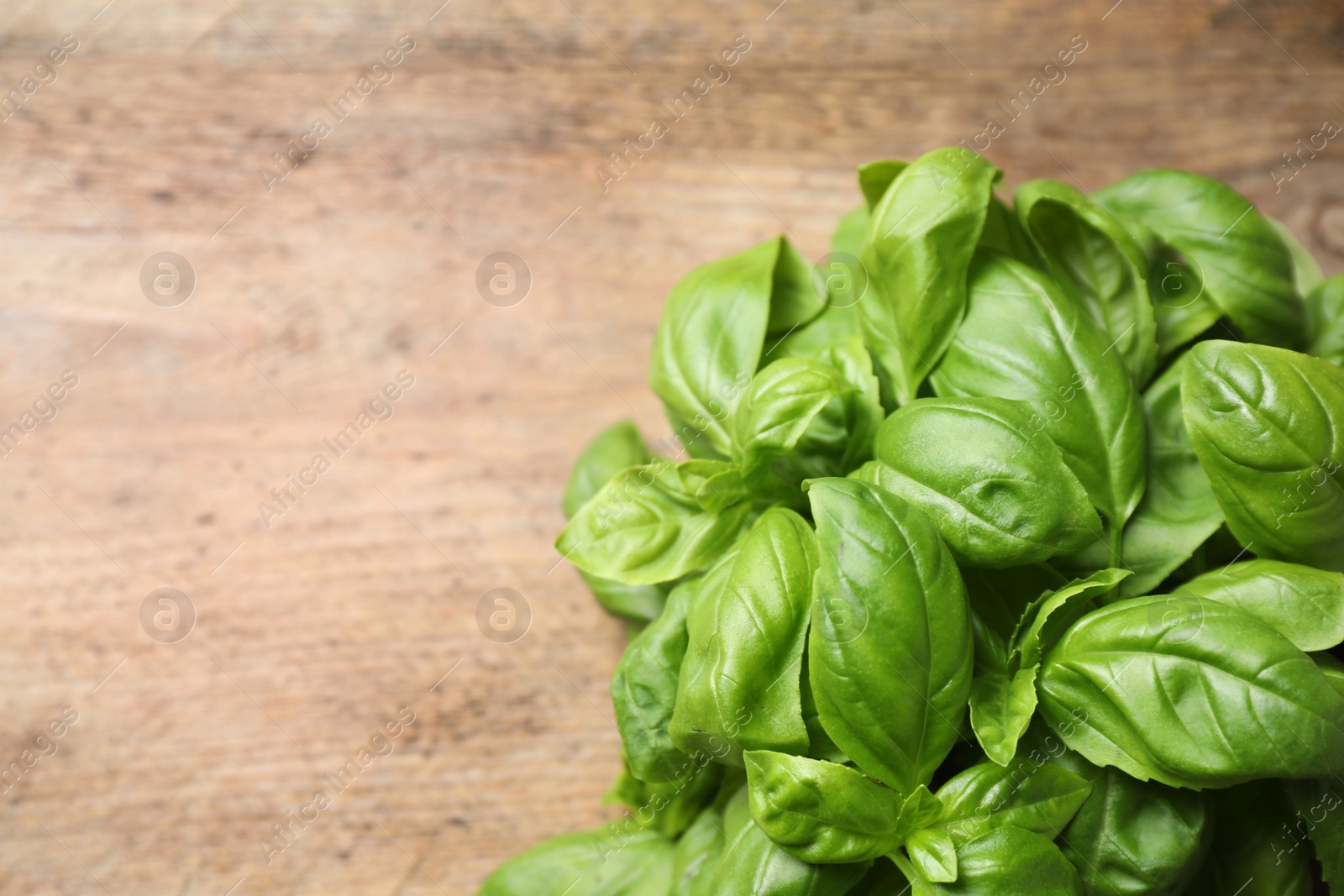 Photo of Fresh basil on wooden table, top view. Space for text