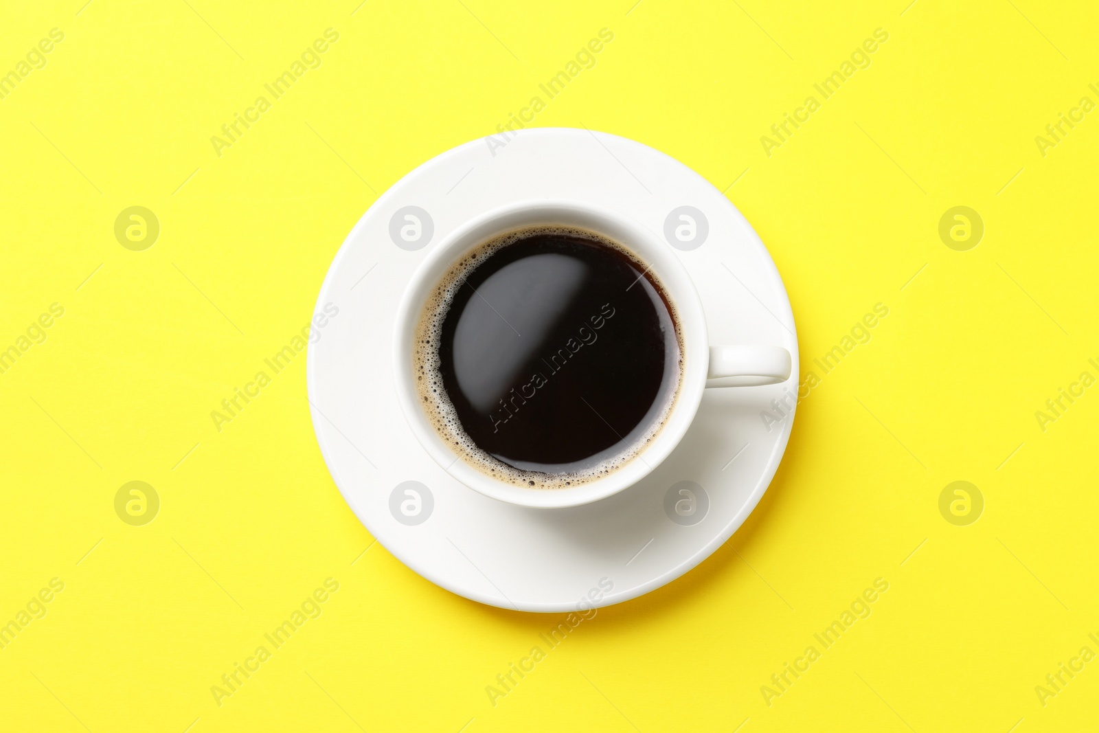 Photo of Cup of aromatic coffee on yellow background, top view