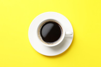 Cup of aromatic coffee on yellow background, top view