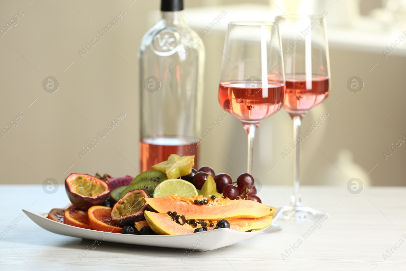 Photo of Delicious exotic fruits and wine on white table