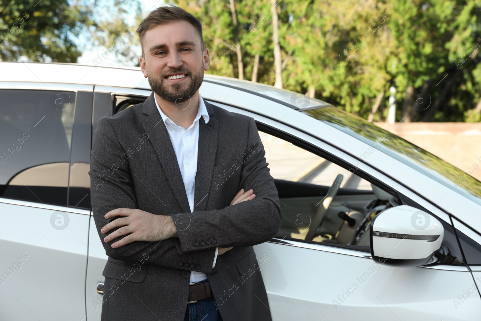 Photo of Handsome young driver near modern car on city street