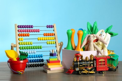 Many different toys on wooden table against light blue background