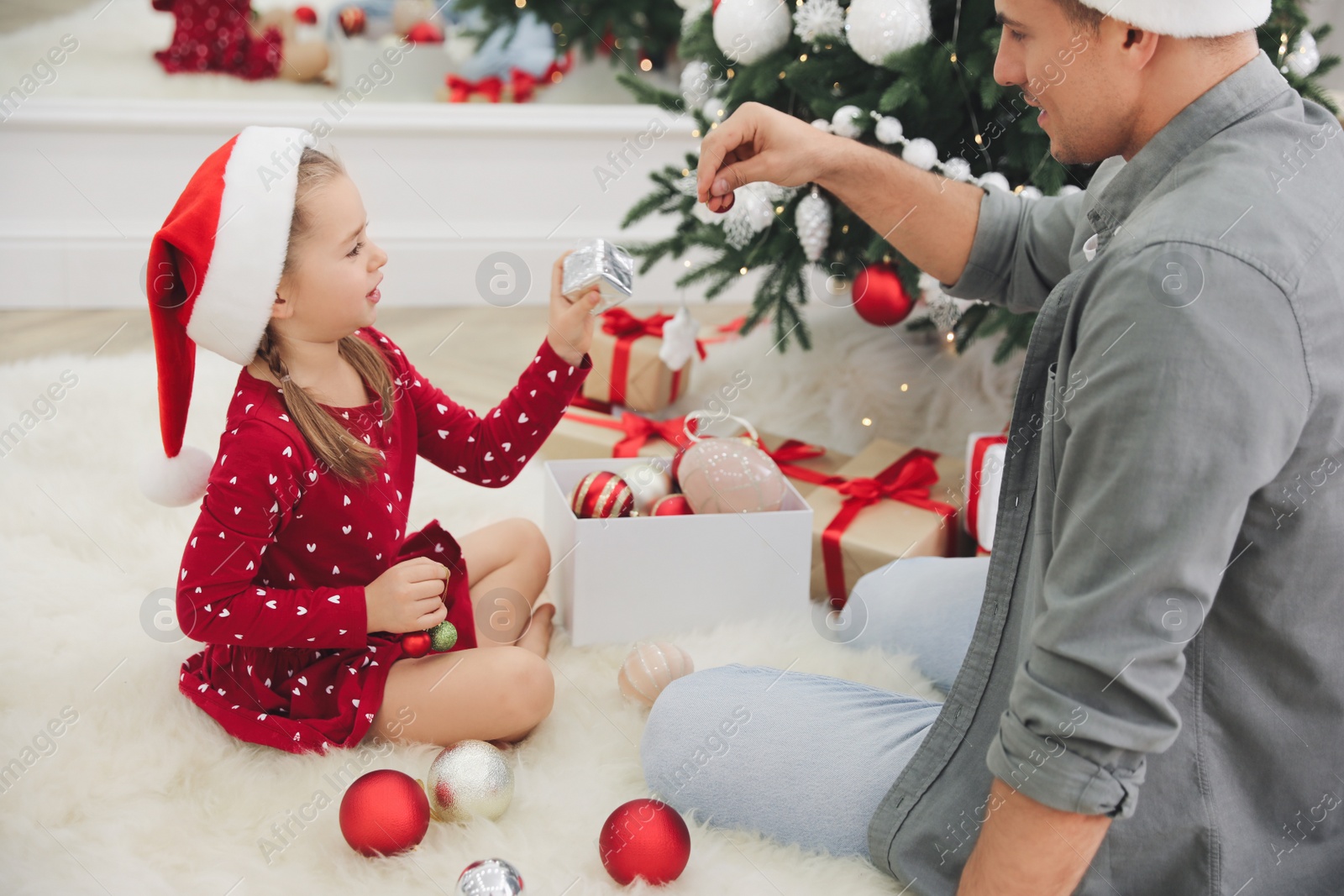 Photo of Father with his cute daughter decorating Christmas tree together at home