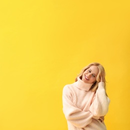 Beautiful young woman wearing warm pink sweater on yellow background. Space for text