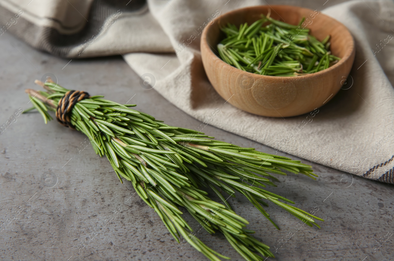 Photo of Bowl with fresh rosemary twigs on grey background