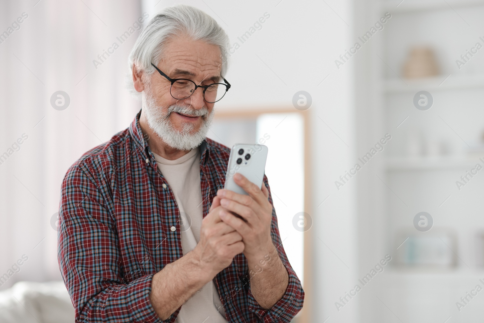 Photo of Portrait of happy grandpa with glasses using smartphone indoors