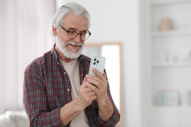 Photo of Portrait of happy grandpa with glasses using smartphone indoors