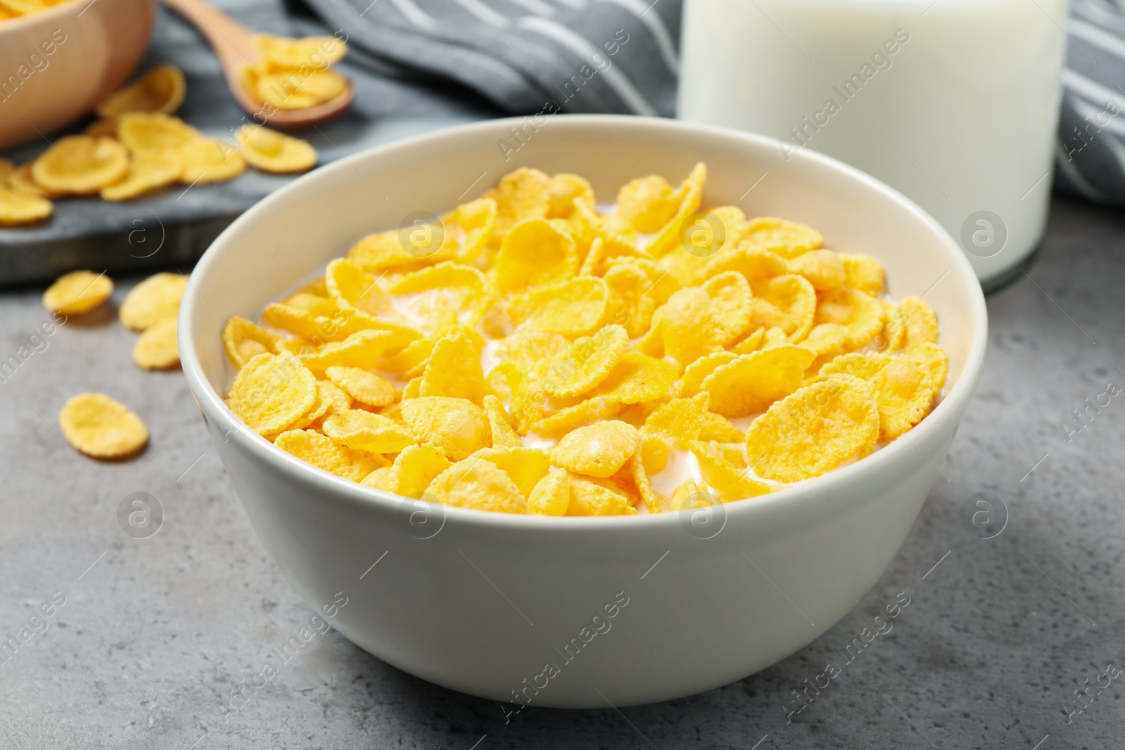 Photo of Tasty corn flakes with milk on light grey table, closeup