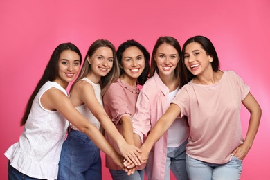 Photo of Happy women putting hands together on pink background. Girl power concept