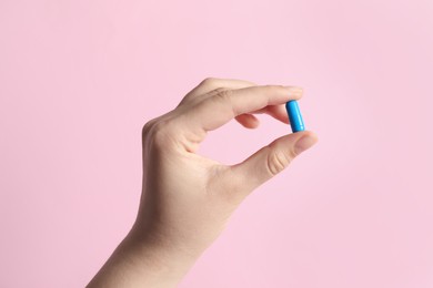 Photo of Woman holding pill on pink background, closeup