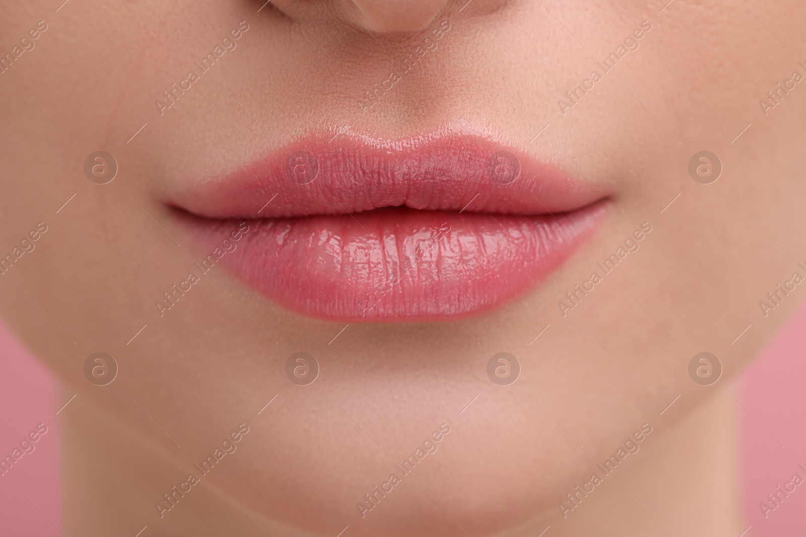 Photo of Young woman with beautiful full lips on pink background, closeup