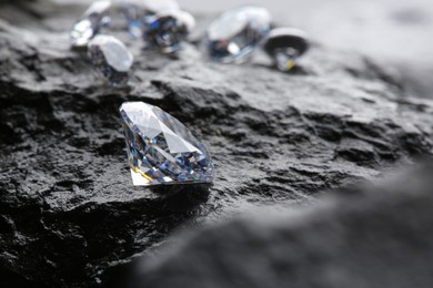 Photo of Different shiny diamonds on wet stone surface. Space for text