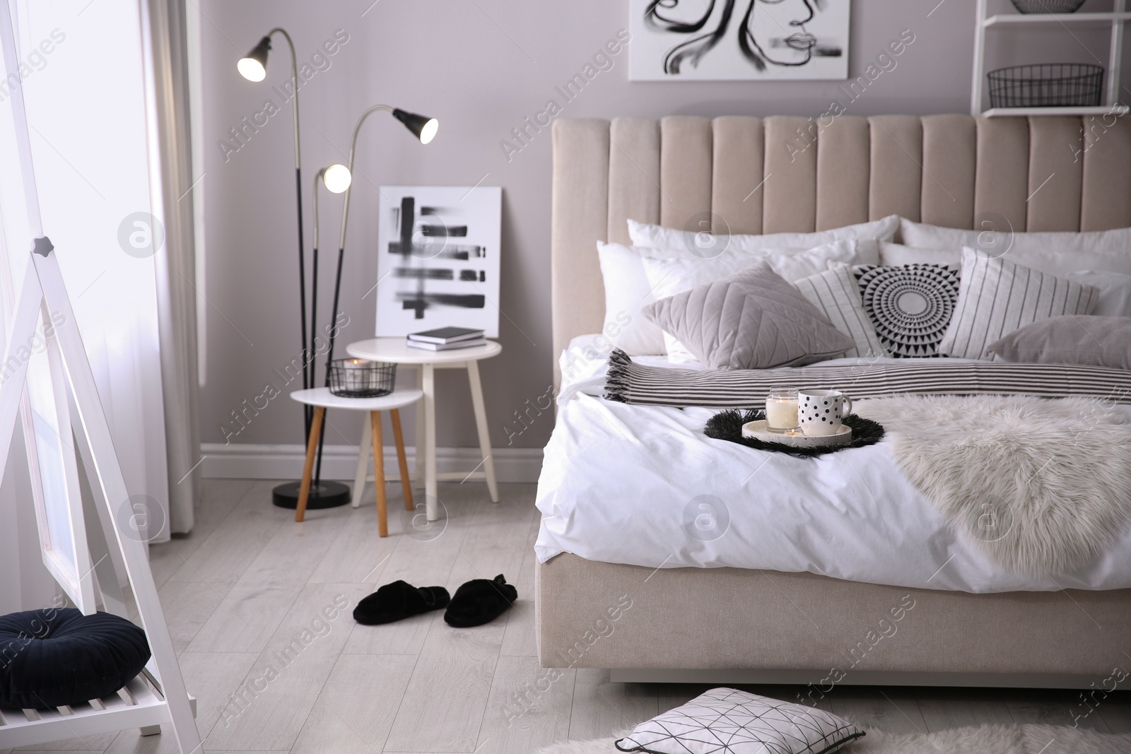 Photo of Cozy bedroom interior with cushions and striped blanket