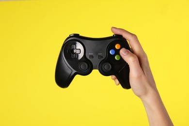 Photo of Woman using game controller on yellow background, closeup