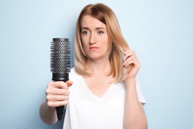 Young woman with hair loss problem on color background