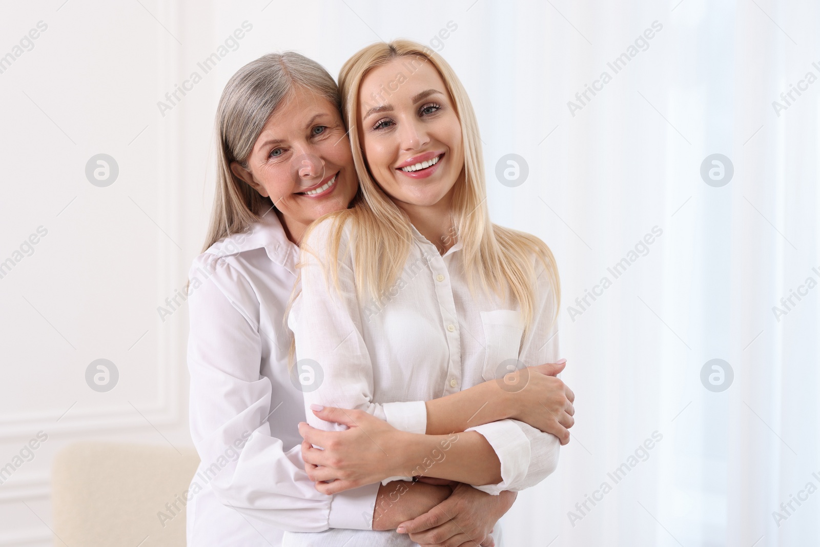 Photo of Family portrait of young woman and her mother near white wall