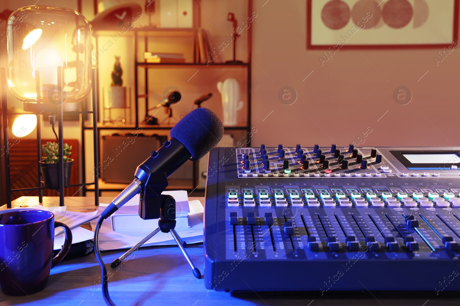 Photo of Microphone and professional mixing console on table in radio studio