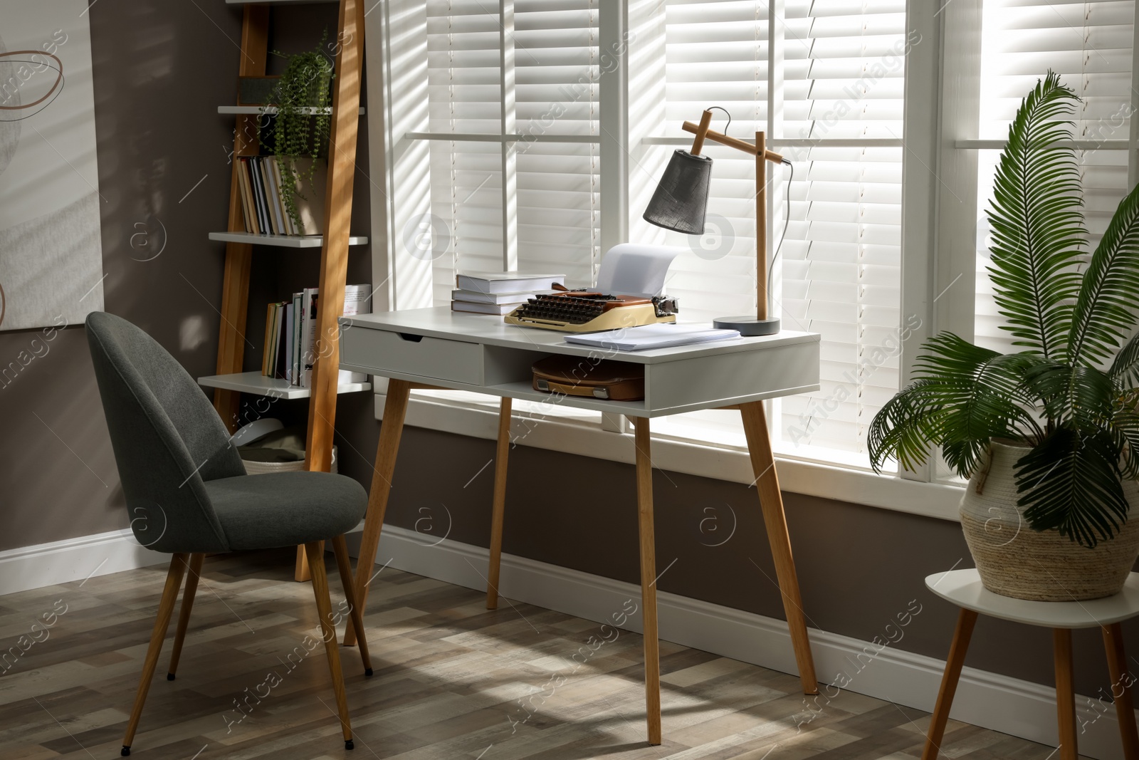 Photo of Comfortable writer's workplace interior with typewriter on desk in front of window