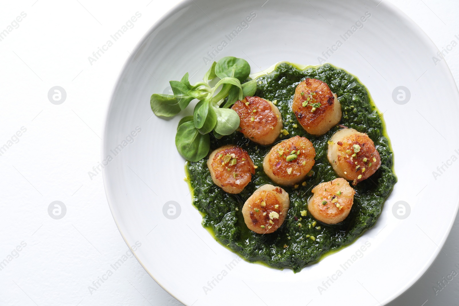 Photo of Delicious fried scallops with tasty sauce and corn salad in bowl on white background, top view